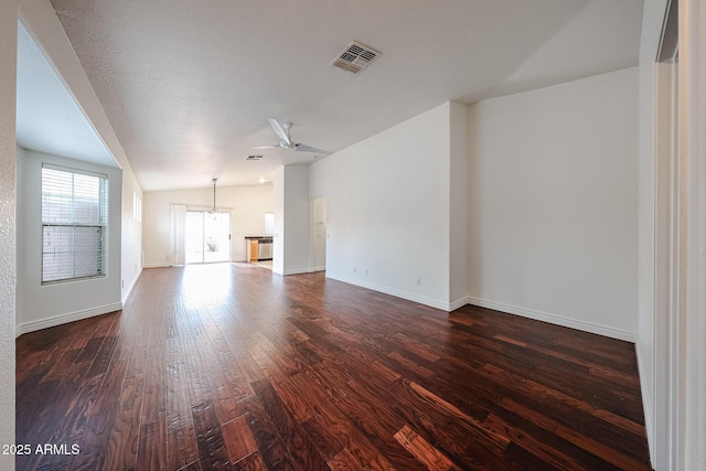 unfurnished living room featuring vaulted ceiling, dark wood-type flooring, and ceiling fan