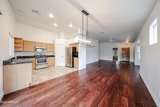 kitchen with pendant lighting, sink, appliances with stainless steel finishes, ceiling fan with notable chandelier, and light wood-type flooring