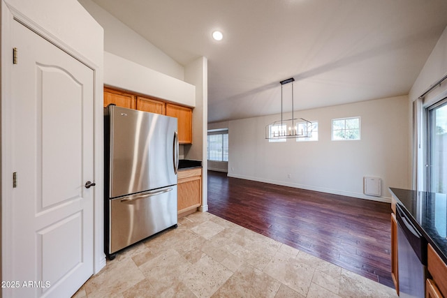 kitchen featuring vaulted ceiling, appliances with stainless steel finishes, pendant lighting, a chandelier, and light hardwood / wood-style flooring