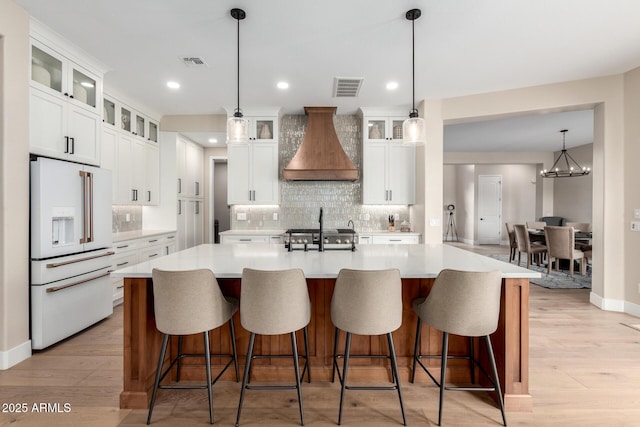 kitchen featuring high end white refrigerator, custom range hood, a large island, and visible vents
