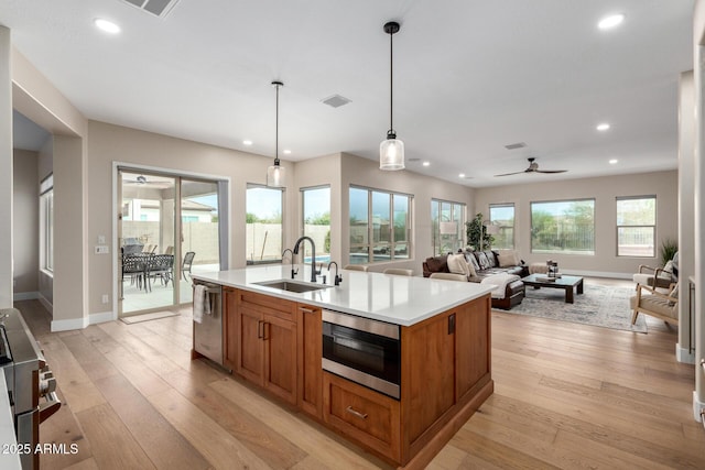 kitchen featuring light wood finished floors, brown cabinets, a sink, and stainless steel appliances