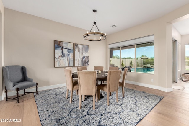 dining room featuring baseboards, light wood-type flooring, and a notable chandelier