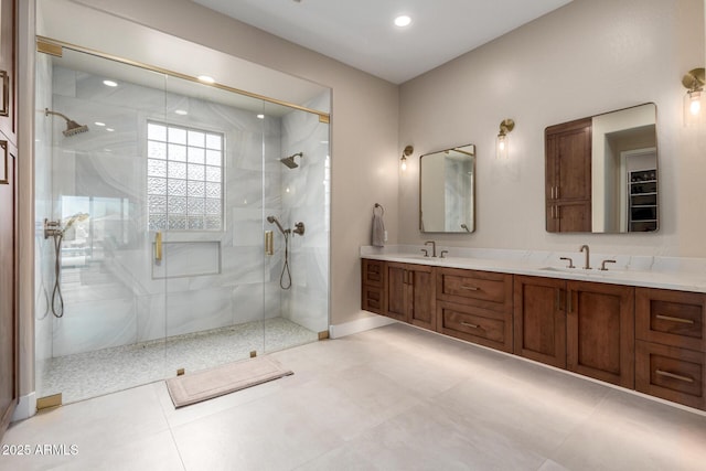 bathroom with a stall shower, double vanity, and a sink