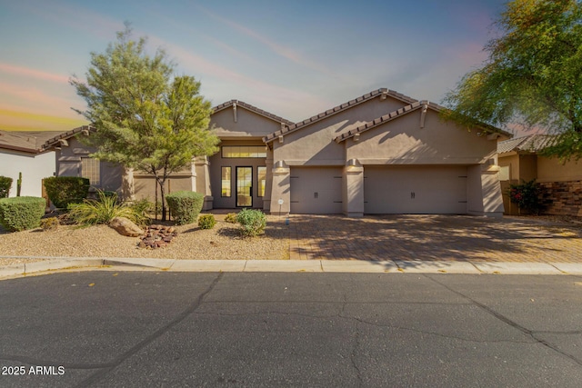 view of front of house featuring stucco siding, driveway, a garage, and a tiled roof