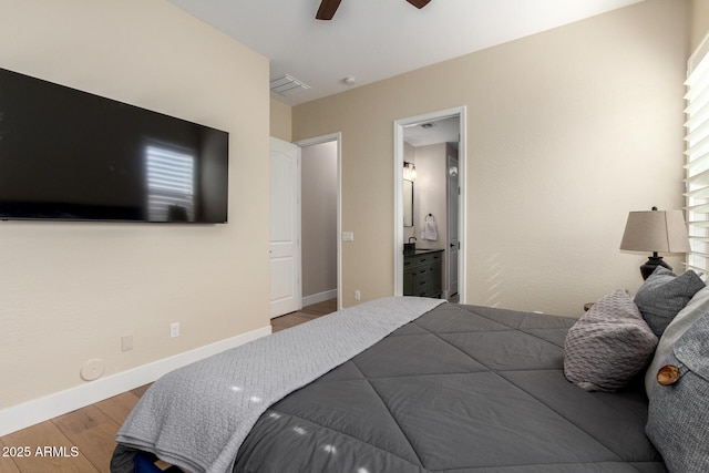 bedroom featuring baseboards, visible vents, wood finished floors, and ensuite bath