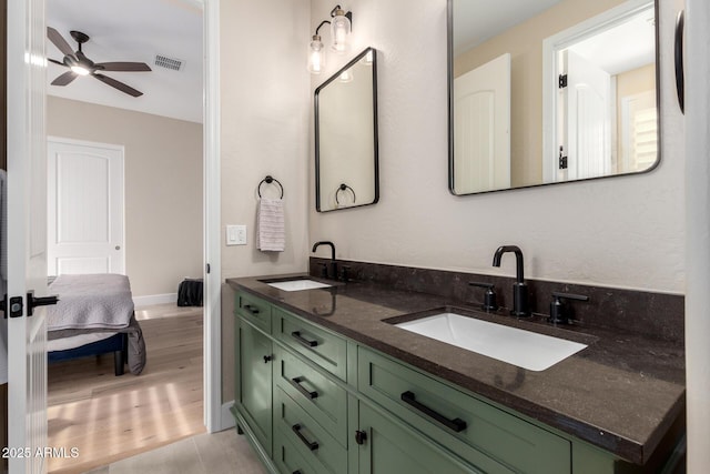 ensuite bathroom with wood finished floors, a sink, double vanity, and ceiling fan