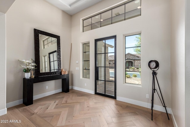 foyer entrance featuring baseboards and a towering ceiling