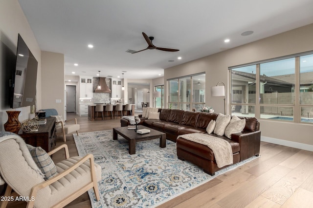 living area featuring baseboards, light wood-type flooring, recessed lighting, and a ceiling fan