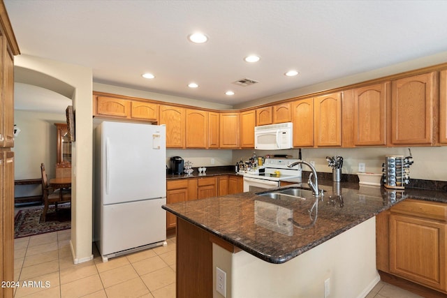 kitchen with kitchen peninsula, white appliances, sink, light tile patterned floors, and dark stone countertops