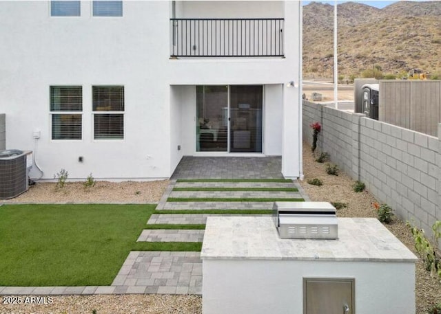 back of house featuring a yard, central AC, a patio, a mountain view, and an outdoor kitchen