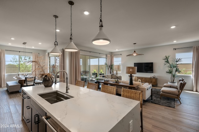 kitchen featuring open floor plan, a sink, light wood-style flooring, and dishwasher