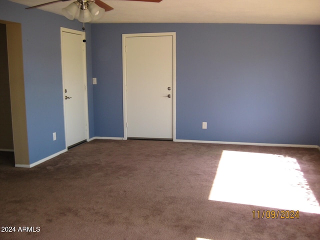 unfurnished room with ceiling fan and dark carpet