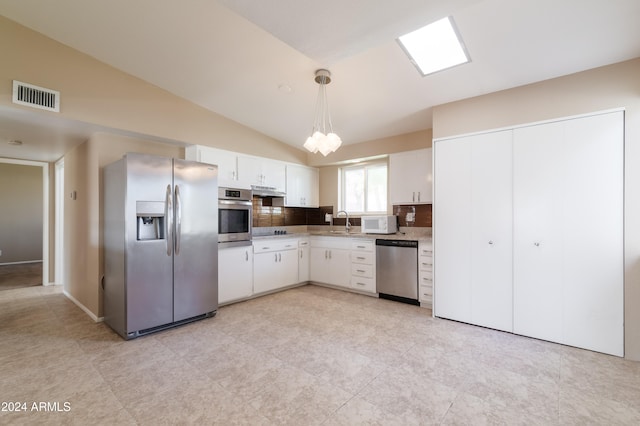 kitchen with appliances with stainless steel finishes, tasteful backsplash, vaulted ceiling, decorative light fixtures, and white cabinetry