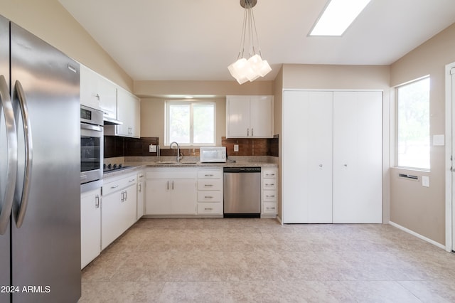 kitchen featuring sink, hanging light fixtures, backsplash, white cabinets, and appliances with stainless steel finishes