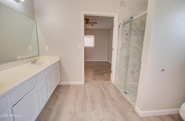 418 E 5th St, Eloy, AZ 85131 - full bathroom with wood finished floors, a marble finish shower, a ceiling fan, double vanity, and toilet