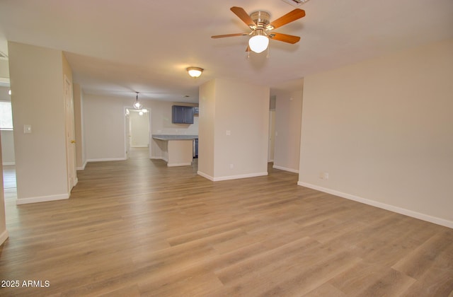 418 E 5th St, Eloy, AZ 85131 - unfurnished living room with baseboards, a ceiling fan, and light wood-style flooring