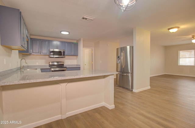 418 E 5th St, Eloy, AZ 85131 - kitchen featuring appliances with stainless steel finishes, a sink, light wood-style flooring, a peninsula, and baseboards