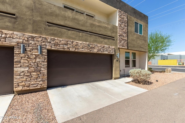 2000 N 36th St Unit 14, Phoenix, AZ 85008 - view of front of house with stone siding, an attached garage, stucco siding, and concrete driveway