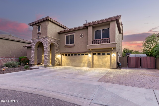 mediterranean / spanish house with stucco siding, an attached garage, fence, stone siding, and driveway