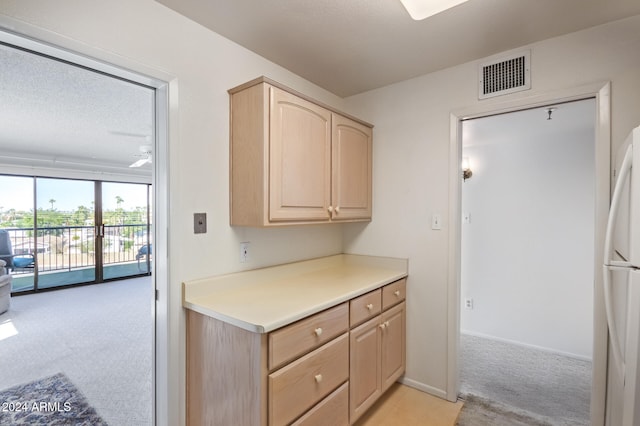 kitchen with light brown cabinets, light colored carpet, a textured ceiling, and white fridge