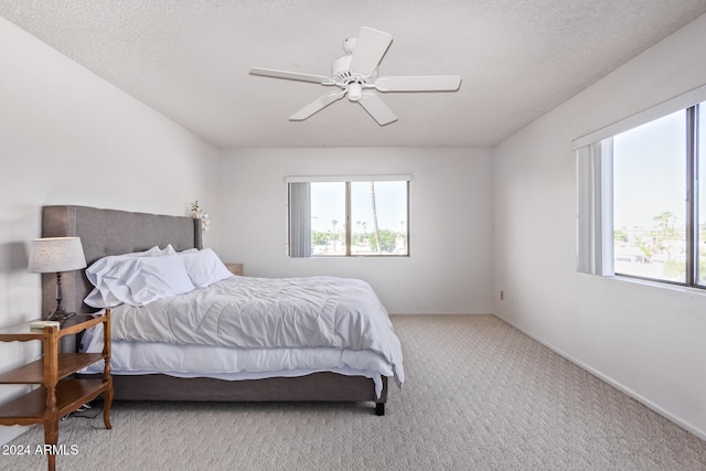 bedroom featuring a textured ceiling, light carpet, and ceiling fan