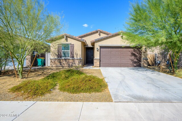 12568 W Orangewood Ave, Glendale, AZ 85307 - ranch-style home with driveway, a tile roof, an attached garage, stone siding, and stucco siding