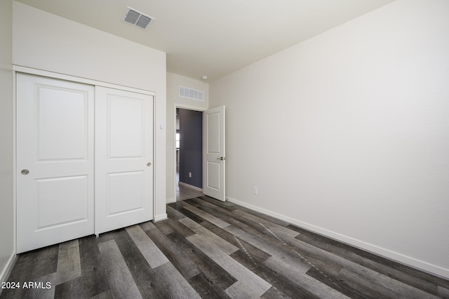 unfurnished bedroom featuring a closet and dark hardwood / wood-style flooring