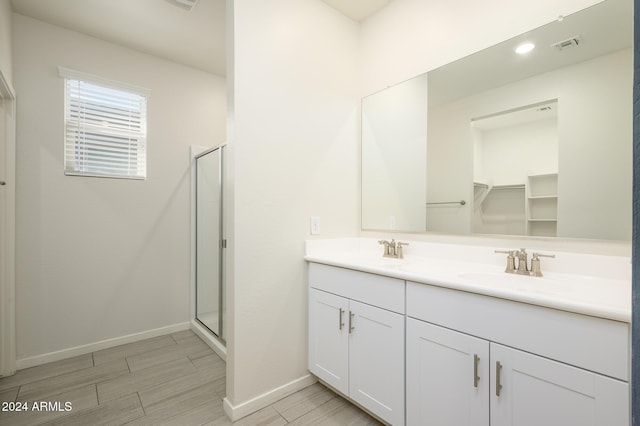 12568 W Orangewood Ave, Glendale, AZ 85307 - full bathroom featuring double vanity, visible vents, a shower stall, wood finish floors, and a sink