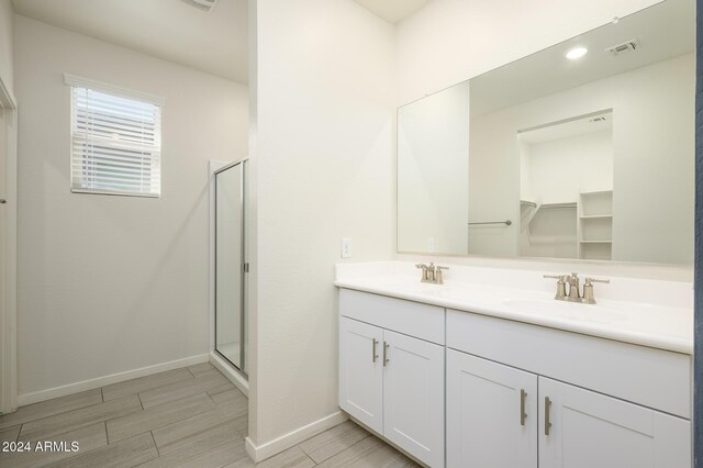 12568 W Orangewood Ave, Glendale, AZ 85307 - full bathroom featuring double vanity, visible vents, a shower stall, wood finish floors, and a sink