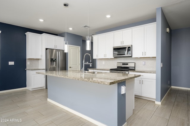 kitchen featuring appliances with stainless steel finishes, an island with sink, and white cabinets