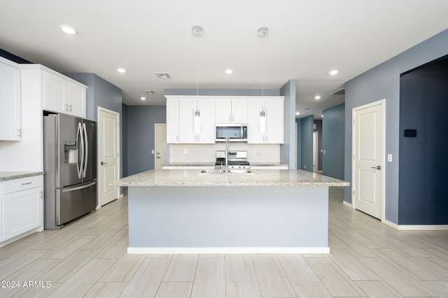 kitchen featuring a kitchen island with sink, stainless steel appliances, light stone counters, and pendant lighting