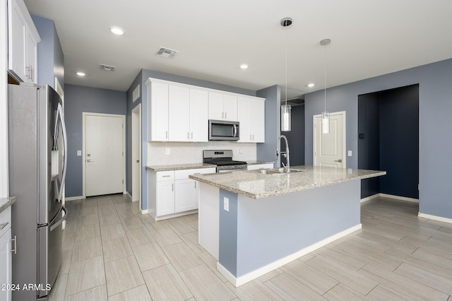 kitchen featuring an island with sink, hanging light fixtures, stainless steel appliances, sink, and white cabinetry