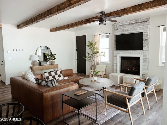 living room featuring beamed ceiling, hardwood / wood-style floors, ceiling fan, and a fireplace