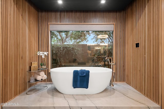 bathroom featuring marble finish floor and a freestanding bath