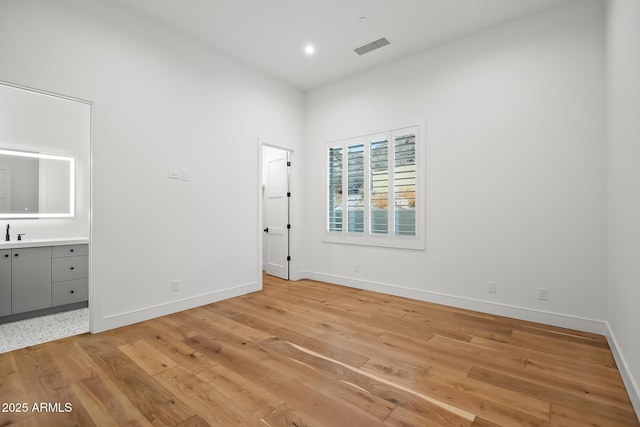 unfurnished bedroom featuring light wood finished floors, visible vents, connected bathroom, and baseboards