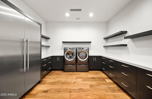 clothes washing area with visible vents, light wood finished floors, recessed lighting, cabinet space, and washer and dryer