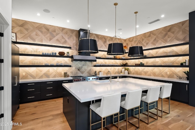 kitchen with a sink, range hood, light countertops, range, and dark cabinets