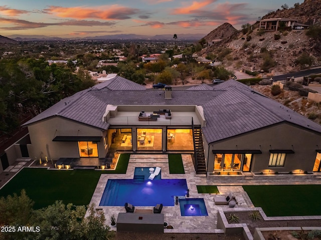 rear view of property with an outdoor pool, a lawn, an in ground hot tub, and a patio area