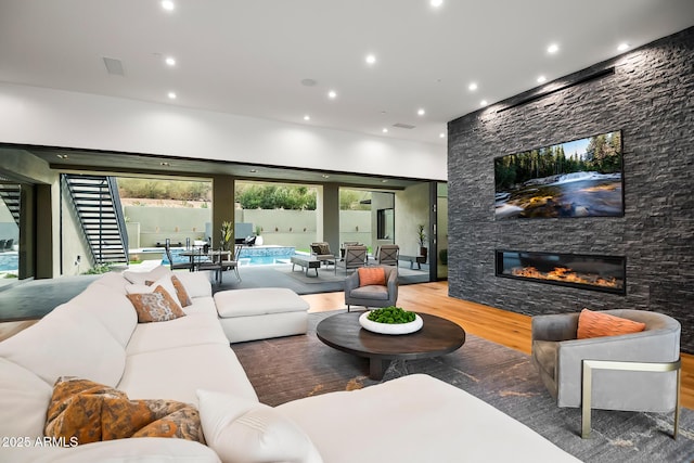 living room featuring visible vents, wood finished floors, recessed lighting, stairway, and a stone fireplace