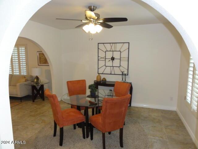 dining area with a ceiling fan, baseboards, arched walkways, and a wealth of natural light