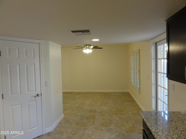 spare room with visible vents, a ceiling fan, and baseboards