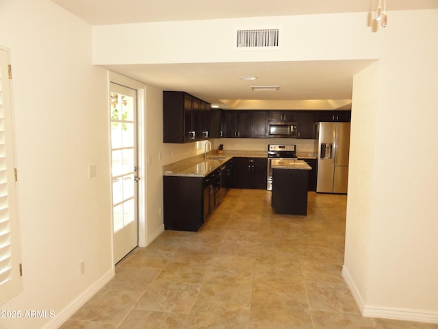 kitchen with light stone counters, baseboards, visible vents, a sink, and stainless steel appliances