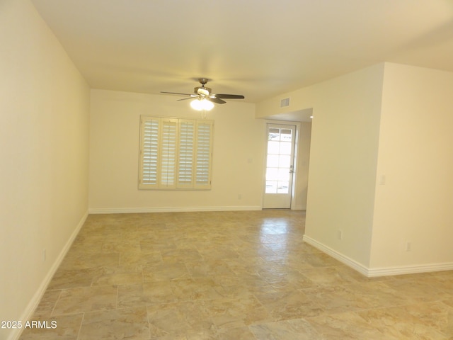 empty room featuring a ceiling fan, visible vents, and baseboards