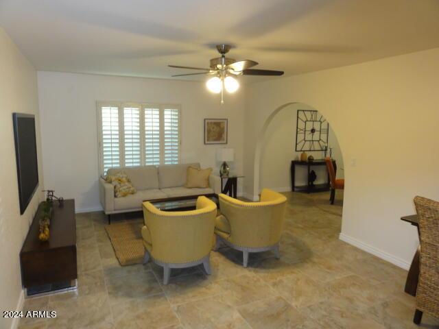 living area with a ceiling fan, arched walkways, and baseboards