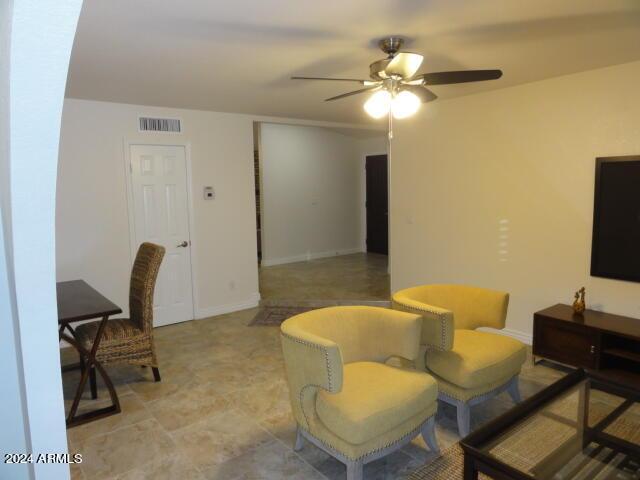 living area featuring visible vents, baseboards, and a ceiling fan