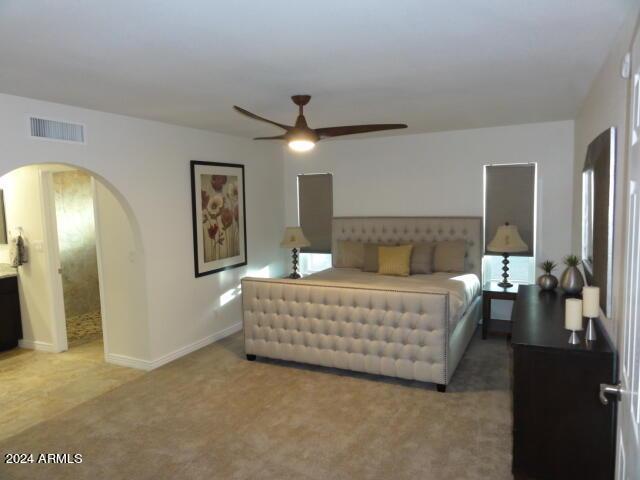 bedroom featuring visible vents, a ceiling fan, arched walkways, carpet flooring, and baseboards