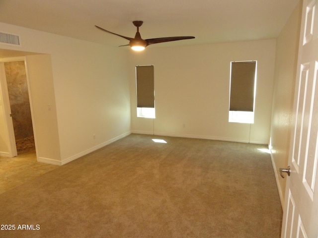 carpeted empty room with visible vents, a healthy amount of sunlight, baseboards, and a ceiling fan