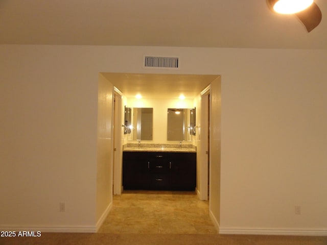 bathroom with visible vents, a sink, baseboards, and double vanity