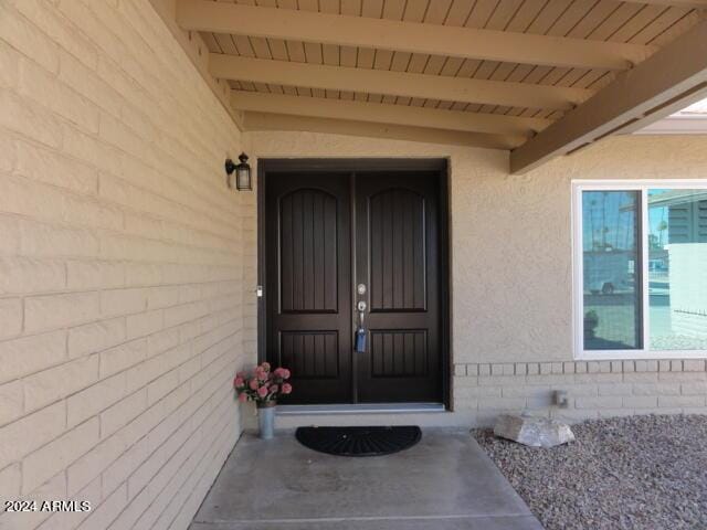 doorway to property featuring stucco siding and brick siding