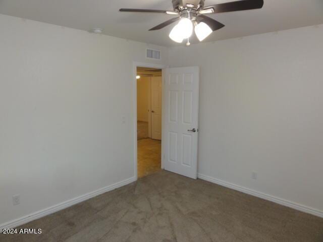 carpeted spare room with baseboards, visible vents, and ceiling fan